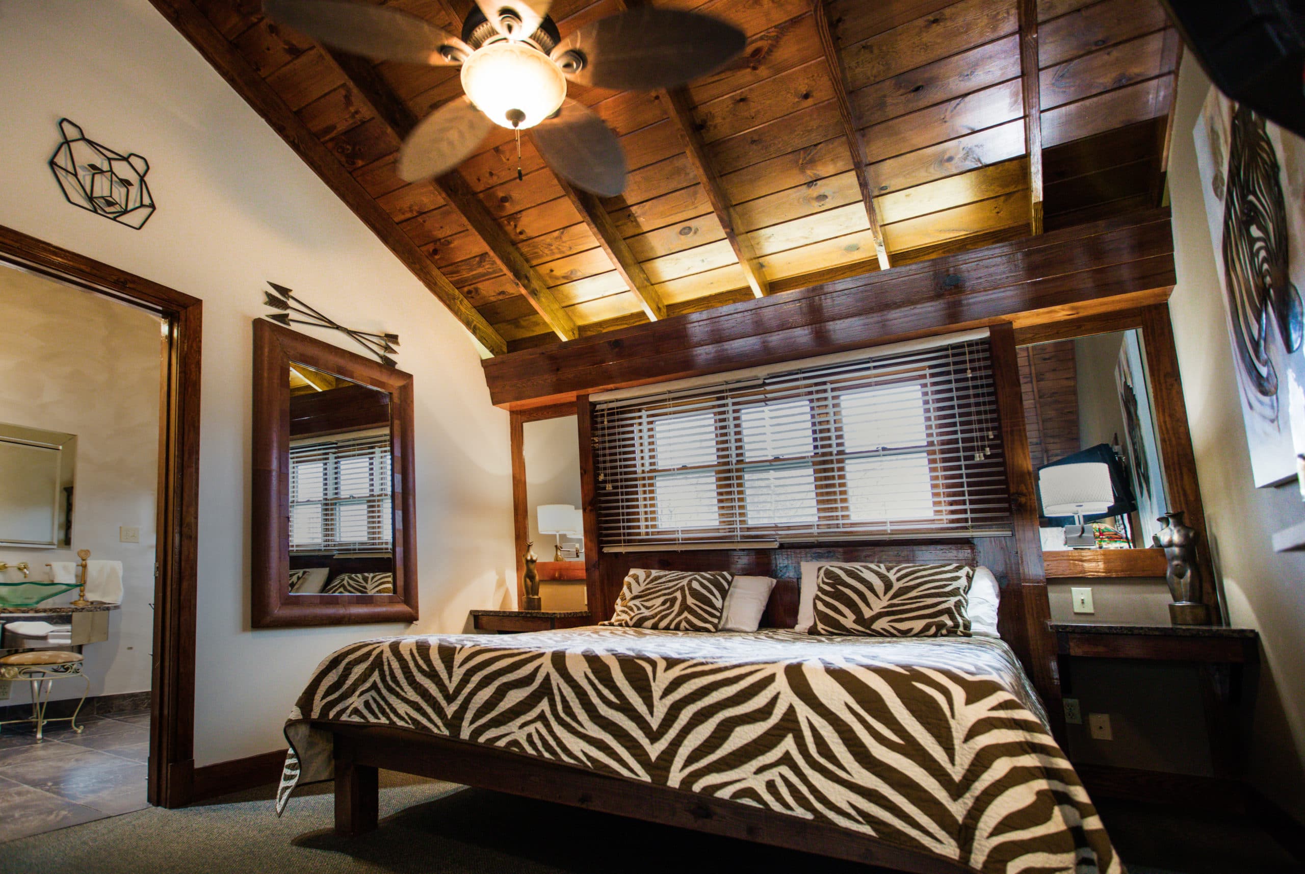 rivers-bend-cabin-04-riverside-retreat-bedroom-tree-design-blanket-wood-ceiling-scaled