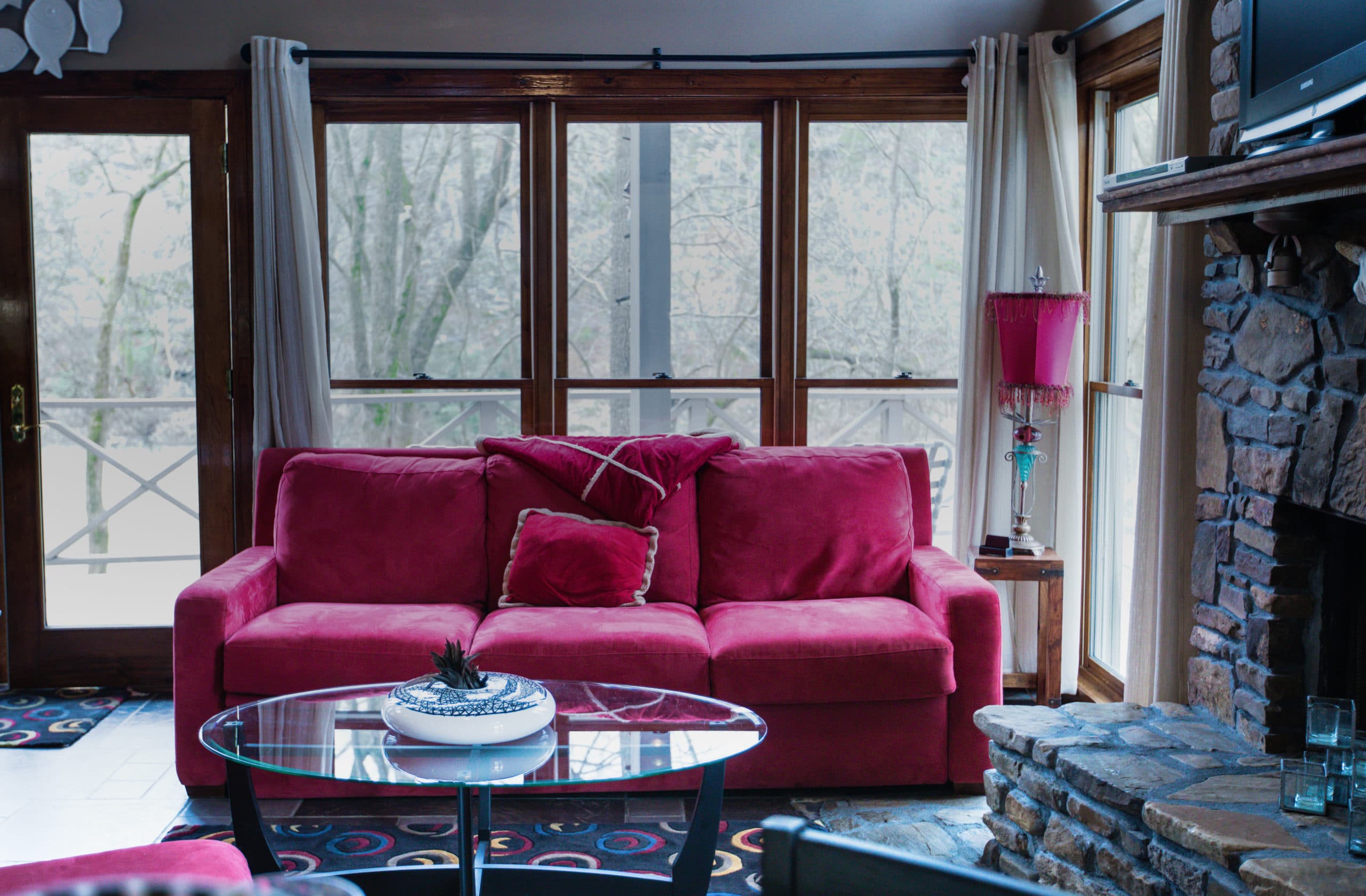 rivers-bend-cabin-04-riverside-retreat-living-room-red-couch-windows-scaled